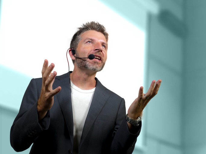 young attractive and confident successful man with headset speaking at corporate business coaching and training auditorium conference room talking giving motivation training from speaker stage