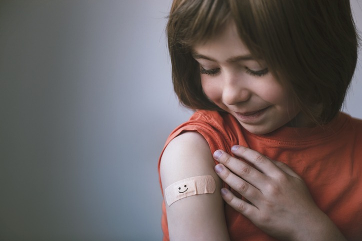 Portrait of smiling little child with adhesive bandage on his hand after vaccination
